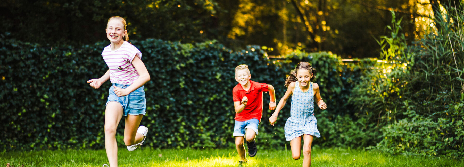 3 kinderen die lopen op het gras in een groene omgeving
