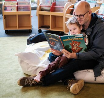 man en kind kijken in boek